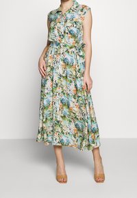 Blommig midiklänning med knäppkrage, korta ärmar, åtsittande midja och en svävande kjol. Materialet har ett livligt tropiskt mönster.