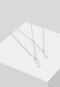 Sølvhalskæder med rektangulære vedhæng, der har spidse ender. Kæderne er sammenkoblet og delikate med en poleret overflade.