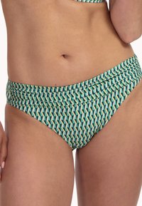 Parte inferior de bikini con un patrón geométrico en verde azulado, amarillo y blanco. La tela tiene una textura suave y un detalle de cintura fruncida.