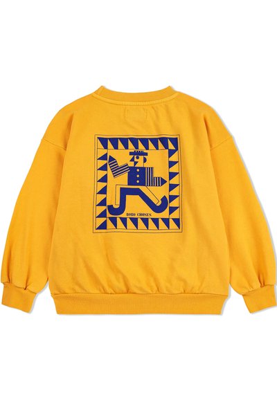 Felpa gialla con un design geometrico blu e una figura all'interno di un bordo quadrato. Polsini e orlo ribattuti, texture del tessuto morbida.