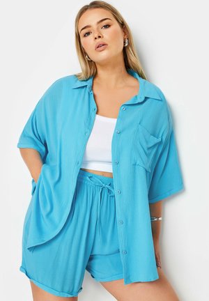 Lichtblauw button-up overhemd met korte mouwen en zak, gecombineerd met bijpassende shorts met een elastische tailleband en trekkoord.