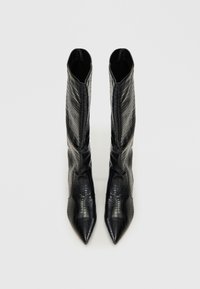 Botas altas negras de tacón hechas de cuero sintético texturizado imitación cocodrilo, con punta afilada y caña ajustada. Forro interior suave.