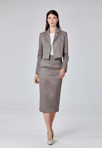 Blazer gris ajusté avec un bouton unique et des manches trois-quarts, associé à une jupe crayon à genoux assortie et des talons de couleur claire.