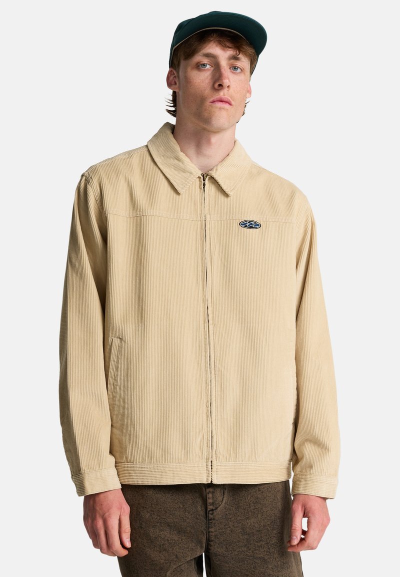 Μπεζ μπουφάν από κορδούρα με γιακά, μπροστινό φερμουάρ, πλαϊνές τσέπες και διακριτικό λογότυπο στο στήθος. Υφασμάτινη υφή με ριγωτό σχέδιο.