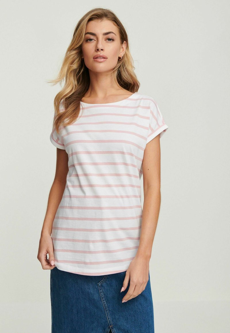 Gestreiftes T-Shirt in Weiß und Hellrosa; lockere Passform mit kurzen, umgeschlagenen Ärmeln; weicher Baumwollstoff; abgerundeter Saum; getragen mit einem Jeansrock.
