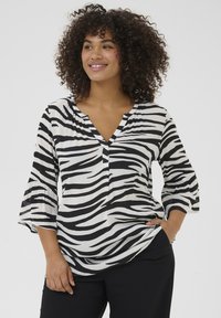 Bluză cu imprimeu zebra alb-negru, cu decolteu în V, mâneci clopot de trei sferturi și croială lejeră. Fabricată dintr-un material ușor, texturat.