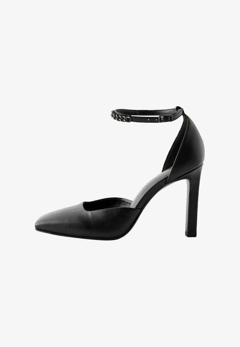 Languettes noires en cuir avec un bout pointu et un côté ouvert. Dotées d'une fine bride de cheville avec des détails en chaîne et d'un talon aiguille.