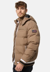 Brown padded jacket with a zippered front, hood, and striped ribbed cuffs. Features an American flag patch and zippered chest pocket.