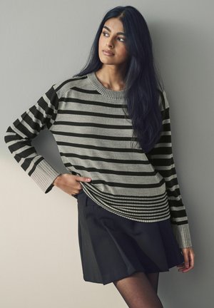 Pull rayé gris et noir avec un col et des poignets côtelés, associé à une jupe noire. Texture lisse, coupe décontractée et motif horizontal.
