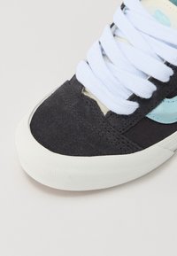 Sorte semskete sneakers med lyseblå detaljer, hvite snørebånd og gummisåle. Har rund tå og sydd detaljer på overdelen.