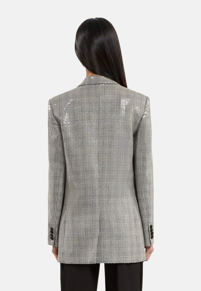 Grijze geruite blazer met glanzende pailletten, gestructureerde pasvorm en een enkele split. Heeft zwarte knopen op de mouwen en een getailleerd silhouet.