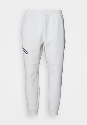 Hvide sweatpants med en blød, glat tekstur. Har bugtede sidelapper og en sort accentstribe. Elastisk talje for justerbar pasform.