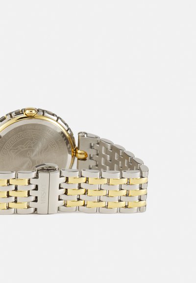 Ezüst és arany tónusú rozsdamentes acél óra szövött karkötővel, kerek tokal és Medusa mintával gravírozott hátsó résszel.