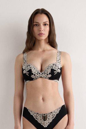 Un soutien-gorge en dentelle noire et un string assorti présentent des motifs floraux beiges complexes, des bords festonnés et des bretelles ajustables. Tissu doux et texturé.