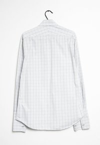 Weißes Hemd mit Muster, das ein Karodesign mit hellblauen und lila Linien zeigt, Kragen, lange Ärmel und abgerundetem Saum hat. Hängt an einem schwarzen Haken.
