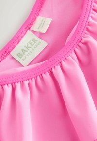 Heldere roze, lichte stof met een geplooide textuur. Bevat een label met "BAKER by Ted Baker" en verzorgingsinstructies.