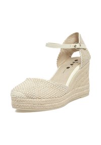 Sandalia de cuña tejida en beige con suela de yute trenzado, correa para el tobillo ajustable y parte superior de tela texturizada. Diseño de punta redondeada con recortes laterales.