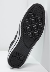 Černá gumová podrážka tenisky s texturovaným diamantovým vzorem a bílými akcenty. Viditelné logo "Converse All Star".