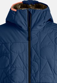 Die marineblaue, gesteppte Kapuzenjacke verfügt über einen schwarzen Reißverschluss, einen orangefarbenen Akzent an der Kragenpartie und geometrische Muster aus Kreisen und Dreiecken.