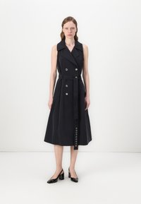 Ναυτικό γιλέκο φόρεμα τζάκετ χωρίς μανίκια με διπλή σειρά κουμπιών, μεγάλα κουμπιά, ζώνη και φαρδυά κωλόστα. Λείος ύφασμα με δομημένη σιλουέτα.