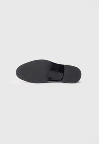 Sorte lædersål, glat tekstur, rund form, minimal detaljer, flad hæl, designet til komfort og holdbarhed.