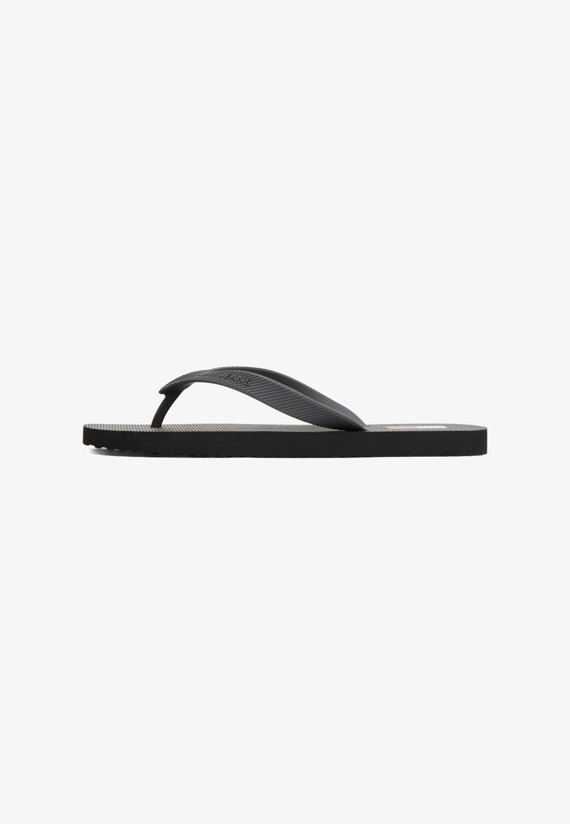 Black flip-flop featuring a textured rubber strap and flat sole with a ridged surface for grip. Simple design with no additional accents.