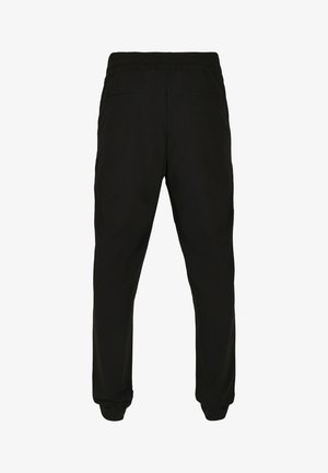 Zwarte, elastische broeken met een tailleband en zijzakken, en elastische boorden. Gladde stof met minimale textuur, ontworpen voor een ontspannen pasvorm.