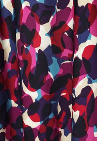Tissu arborant un motif abstrait coloré dans des nuances de rouge, rose, violet, bleu et crème, avec une surface lisse et texturée et des formes variées.