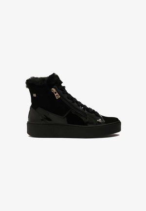 Schwarze Knöchelstiefel mit einem glänzenden Lackleder- und Wildlederobermaterial, ausgestattet mit einem Fellbesatz, goldenen Details und einer dicken schwarzen Sohle.