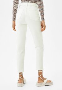 Vita högmidjade jeans med rak passform, som har bakfickor och är ihopparade med beige strappy platåskor.