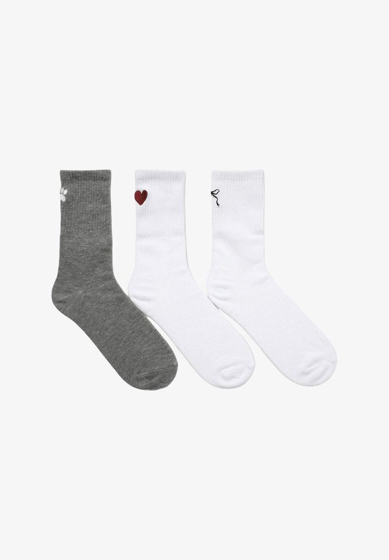 Tre paia di calzini da uomo: uno grigio con una stampa a forma di zampa bianca, due bianchi con un cuore rosso e un fiocco nero. Misura in misto cotone, con texture a coste.