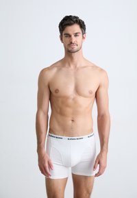 Boxer-briefs blancs avec une ceinture noire arborant le logo "BJÖRN BORG". Tissu lisse, design ajusté et longueur mi-cuisse.