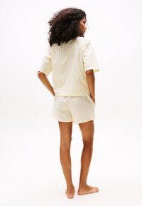 Kort, stripete gul og hvit bomulls sengetøy sett med en boksformet topp og shorts. Stoffet ser mykt ut med en avslappet passform.