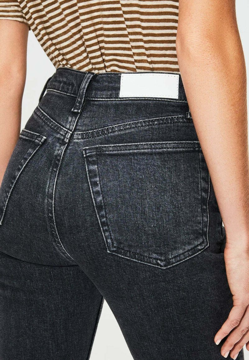 Jeans neri a vita alta realizzati in denim, con tasche posteriori, etichetta in pelle bianca e leggera scoloritura sulla superficie del tessuto.