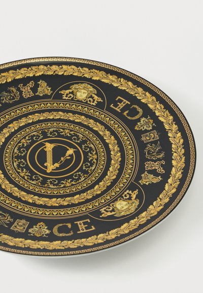 Μαύρο διακοσμητικό πιάτο με περίτεχνα χρυσά λουλουδένια μοτίβα, κεφάλια Μέδουσας και τη λέξη «VERSACE» γύρω από την άκρη σε περίτεχνους χαρακτήρες.