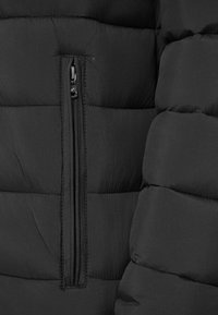 Secțiune de jachetă puffer neagră cu o textură netedă, având panouri quilted orizontale și un detaliu cu buzunar cu fermoar pe față.