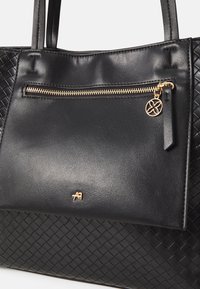 Czarna skórzana torebka o plecionej teksturze, z przednią kieszenią na suwak z złotym okuciem i małym ozdobnym zawieszką.