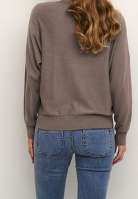 Maglione grigio a maglia con una vestibilità rilassata, orlo a costine e maniche lunghe, abbinato a jeans skinny blu con un classico design della tasca posteriore.