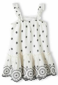 Robe blanche sans manches avec broderie florale noire, bretelles volantées et ourlet en couches présentant des motifs circulaires et en spirale. Tissu texturé.