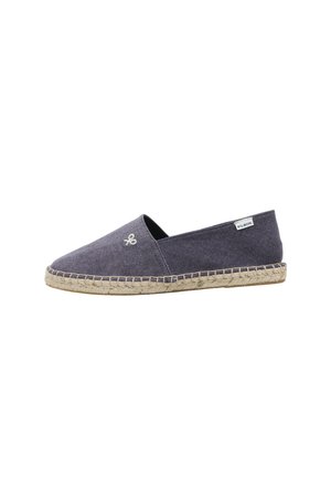 Alpargata de lona azul marino con suela de cuerda beige, pequeño logo bordado blanco cerca de la punta y una etiqueta de tela blanca en el talón.