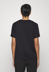 T-shirt noir à manches courtes en tissu lisse. Le dos présente un design simple avec un col rond et une coupe décontractée.
