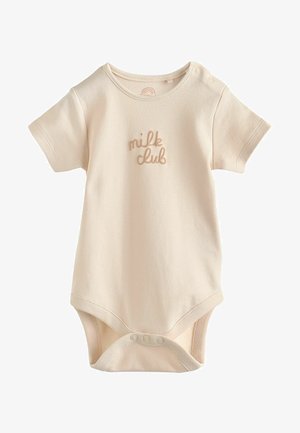 Vaate lyhythihaisella vaaleanbeigeillä bodyllä, joka on valmistettu pehmeästä puuvillasta. Siinä on tikattu "milk club" -teksti vastaavassa sävyssä ja nepparit alaosassa.