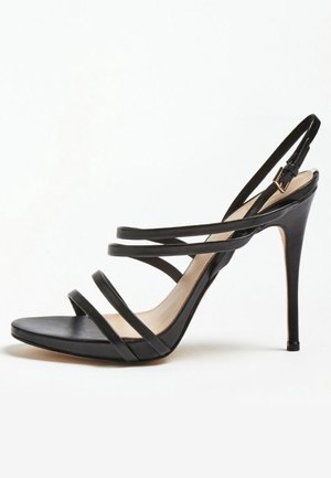 Sort højhælet sandal med tyndt remdesign, åben tå og ankelrem. Glat lædermateriale med beige indersål og stilethæl.
