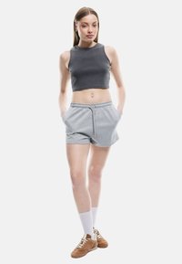 Top corto gris de canalé, combinado con pantalones cortos grises con cintura elástica y bolsillos laterales, usados con zapatillas marrones.