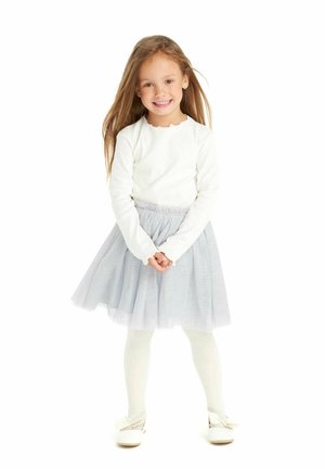 Biała bluzka z długim rękawem i falbaniastym dekoltem, jasnoszara spódnica z tiulu, dobierane rajstopy oraz białe buty z kokardkami. Włosy długie i brązowe.