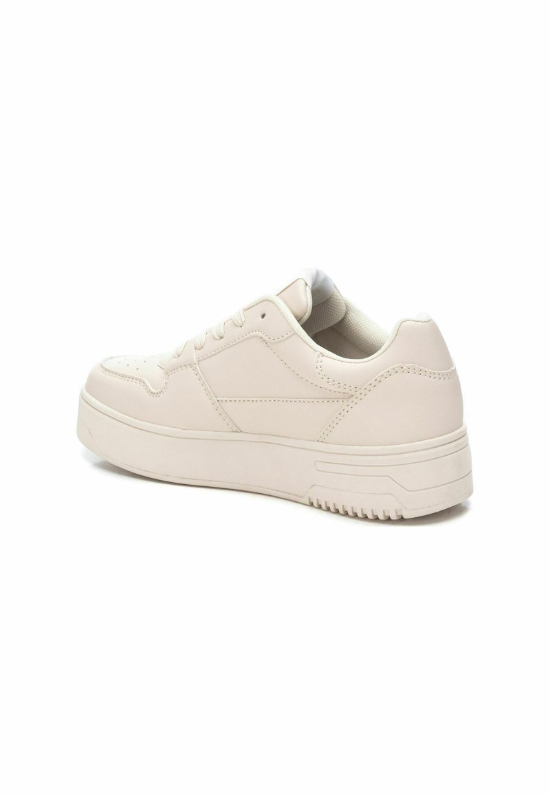 Baskets beiges à tige basse avec une semelle épaisse, lacées à l'avant et avec un col rembourré, présentées sous un angle arrière sur un fond blanc.