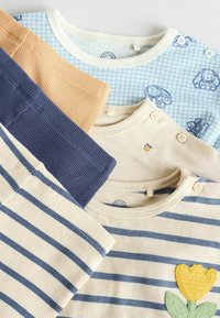 Fünf Kinderhemden in verschiedenen Farben: hellblau kariert, senfgelb, marineblau gerippt, cremefarben mit blauen Streifen und cremefarben mit einer gelben Blumenapplikation.