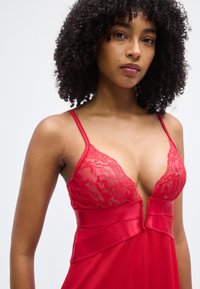 Κόκκινο σατέν νυχτικό με δαντέλα στο μπούστο, ρυθμιζόμενους ιμάντες, βαθύ V-λαιμόκοψη και λεία υφή.