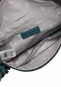 Tyrkysová kožená taška uvnitř s kapsou na zip, šedá látková podšívka s opakujícím se vzorem loga a značková etiketka přišitá uvnitř.