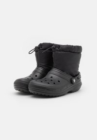 Bottes d'hiver noires avec une tige en nylon rembourrée, des côtés perforés, des semelles en caoutchouc et un système de fermeture à cordon pour un ajustement réglable.